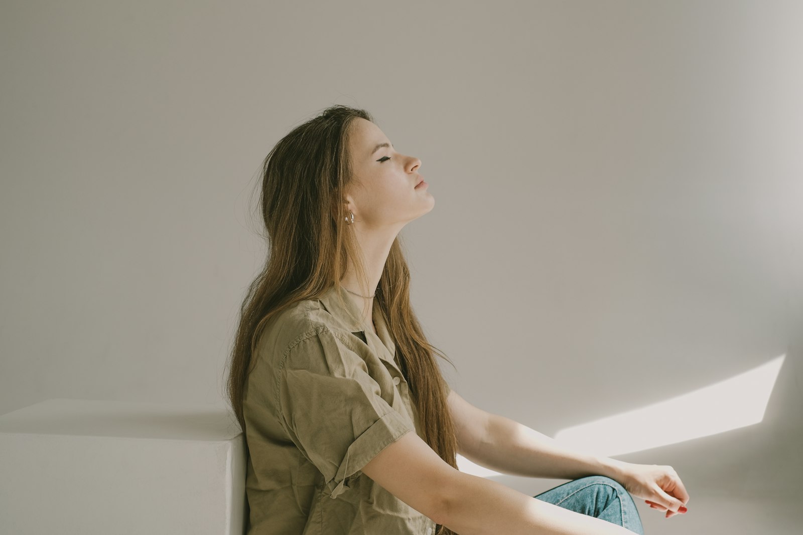 A woman sitting quietly in daylight, her head tilted back and eyes closed