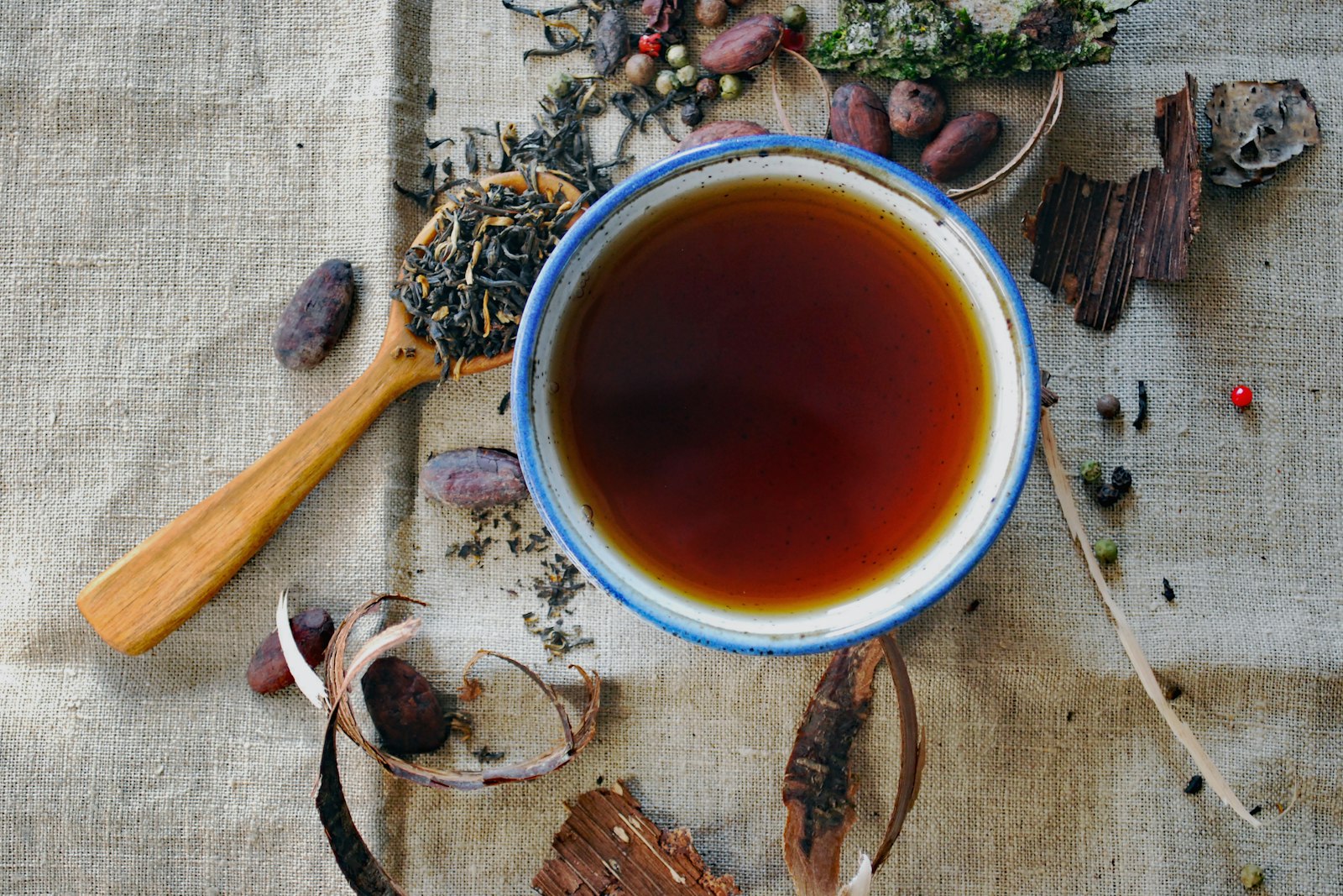 A bowl of herbal infusion surrounded by dried herbs