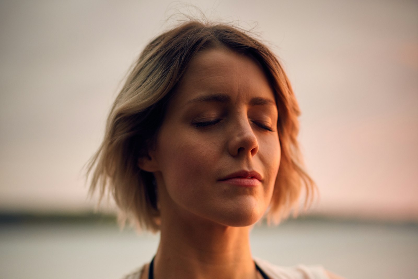 A woman breathing slowly with her eyes closed at dusk