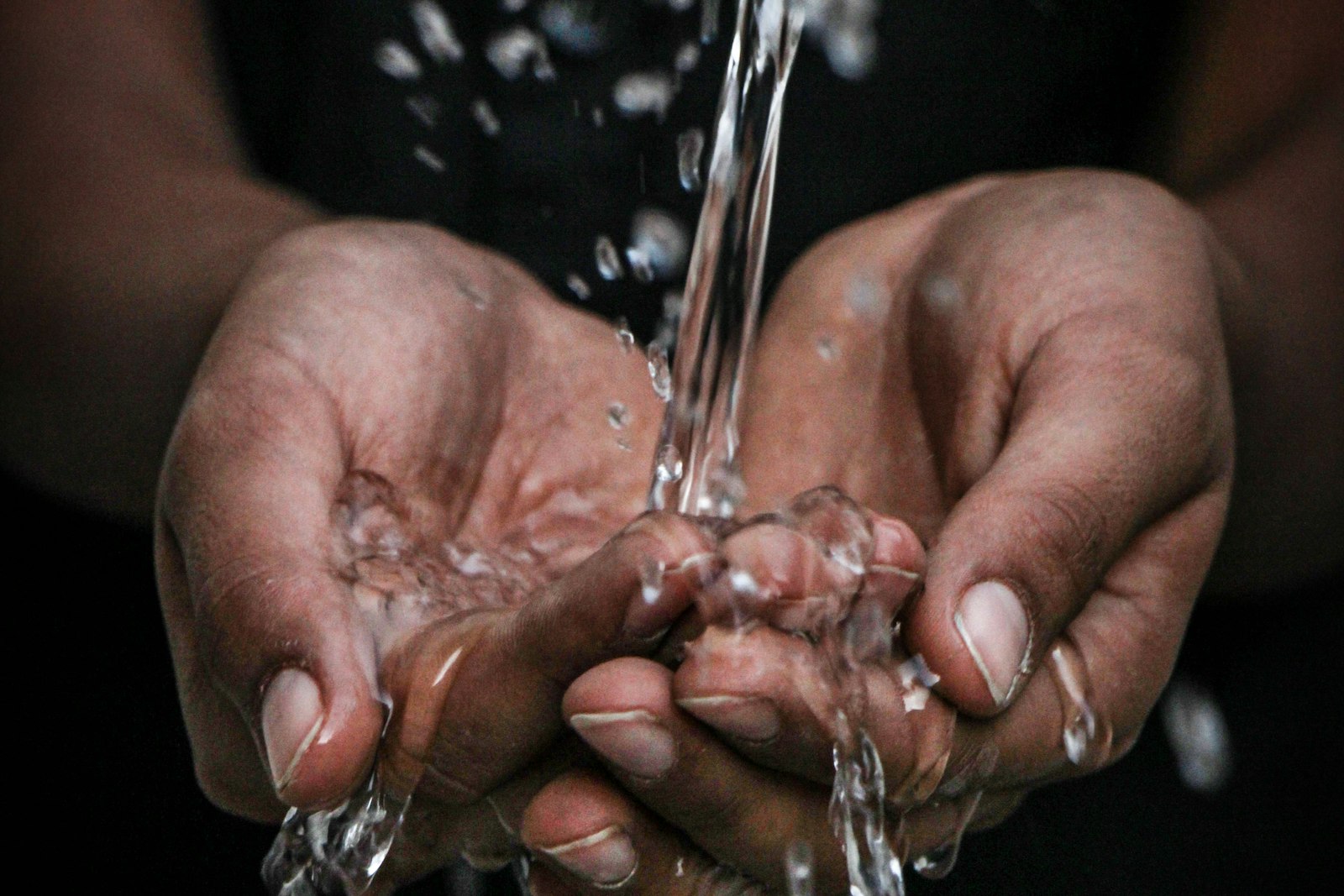 Cupped hands catching clear running water