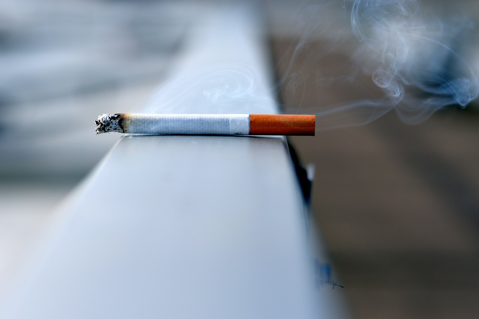 A lit cigarette left resting on a ledge