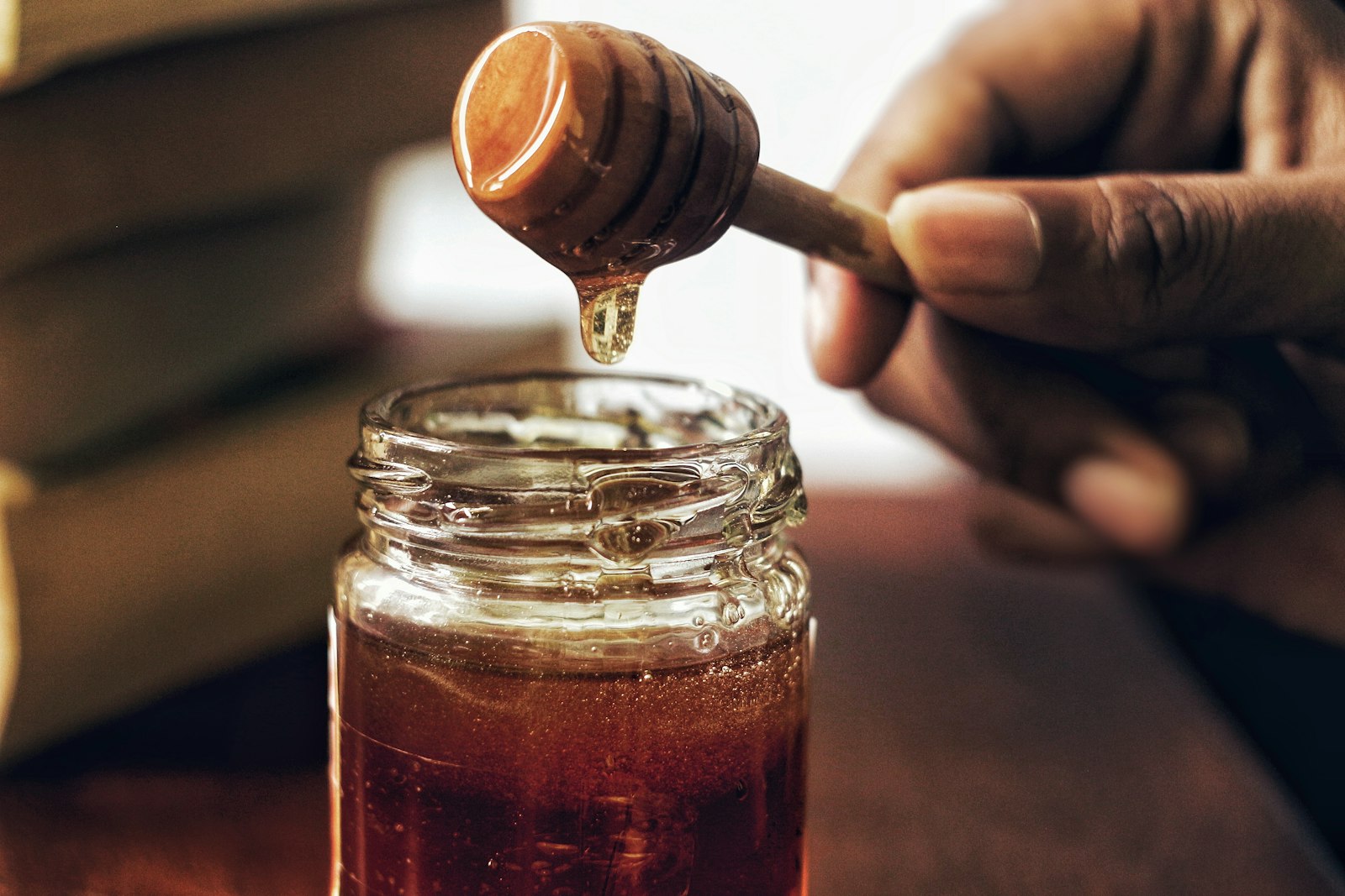 Honey being lifted from a jar with a wooden dipper