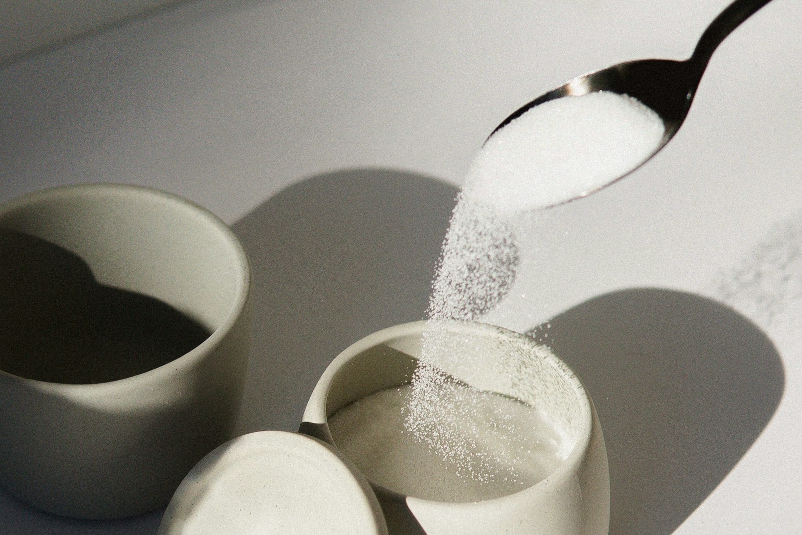 Sugar spooned into small cups in raking light