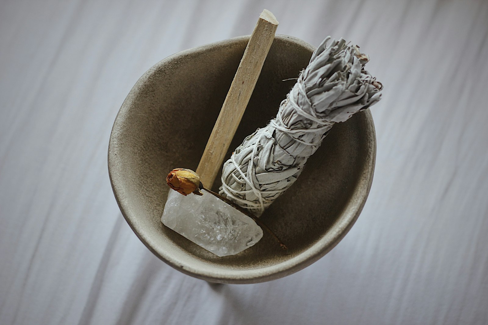 A sage bundle and palo santo resting in a ceramic dish