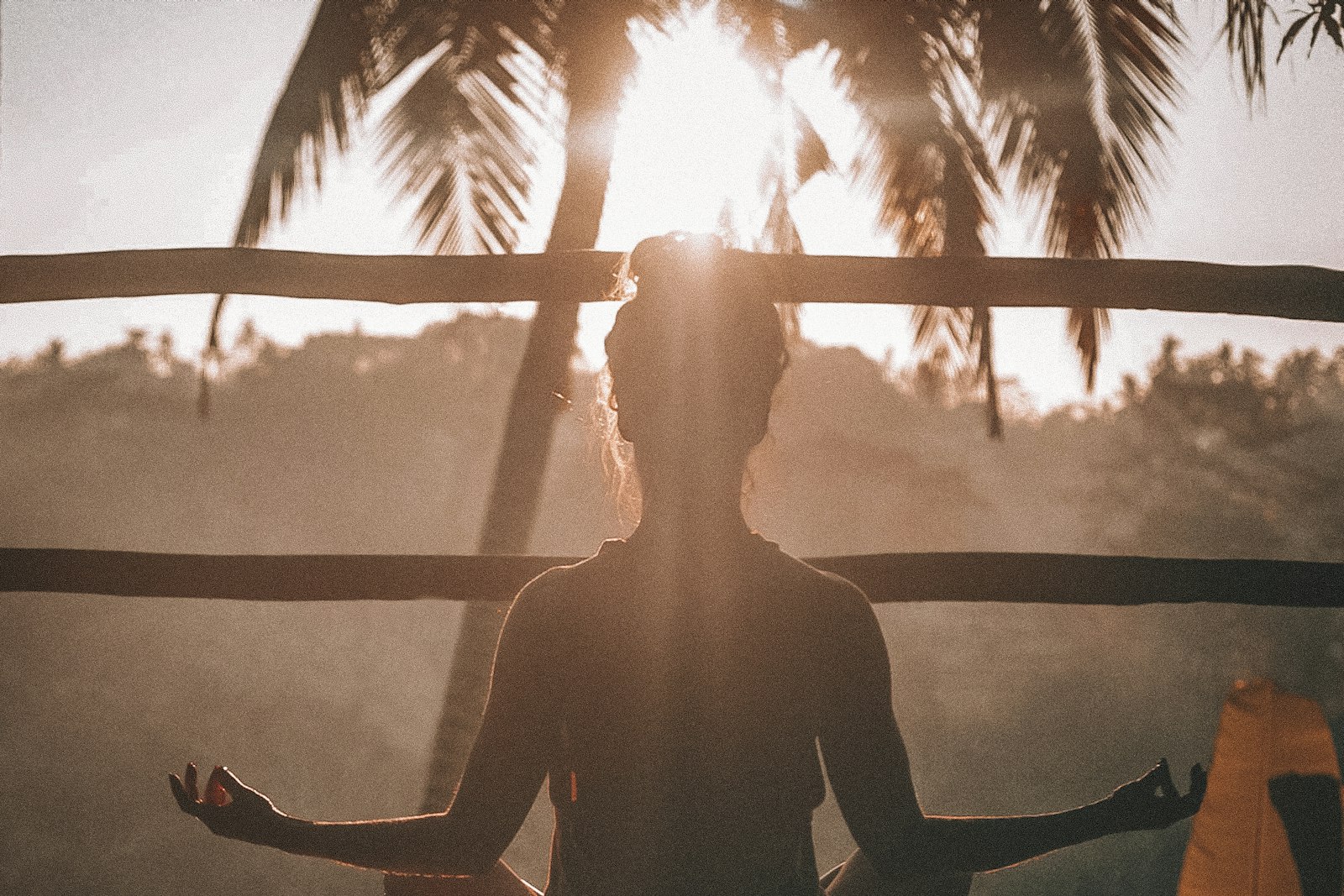 A person meditating in silhouette at sunset