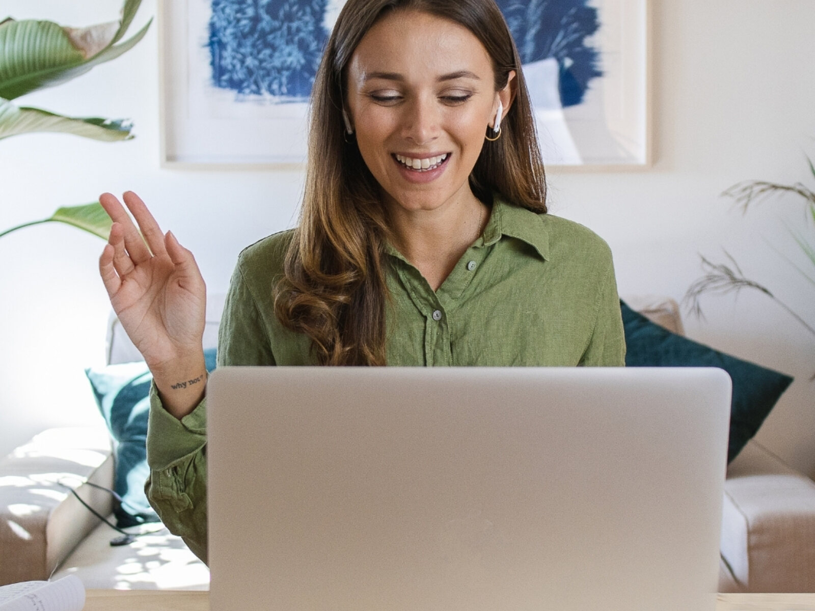 A client smiling warmly during an online session at home, laptop open in front of her