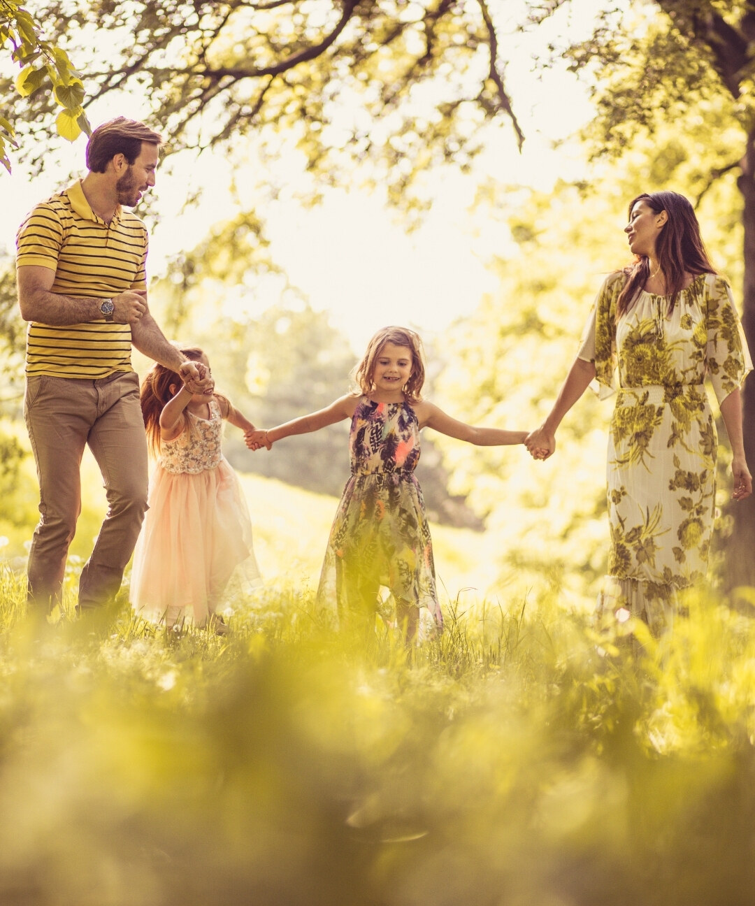 A family walking hand in hand through a sunlit meadow